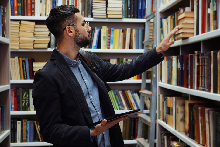 Male librarian looking through the shelves of a library